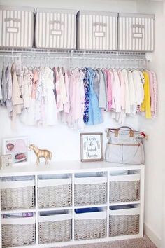 an organized closet with baskets and clothes hanging on the wall, along with baby's clothing