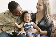 a man and woman sitting on a couch with a baby