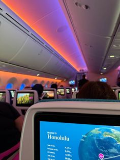 the interior of an airplane with people watching television