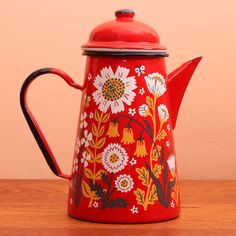 a red tea pot with flowers painted on it