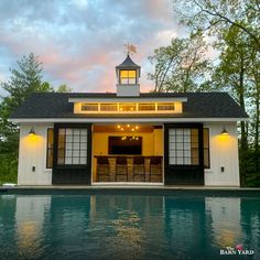 a small pool house with a bar in the center and windows on each side that overlooks an outdoor swimming pool