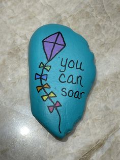 a painted rock with the words you can soar written on it and a kite