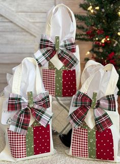 three bags with bows on them sitting next to each other in front of a christmas tree