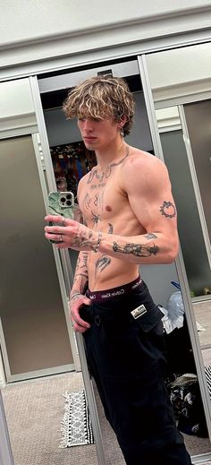 a man with tattoos standing in front of a mirror