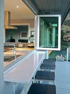 an outdoor kitchen with stainless steel counter tops and stools next to the bar area