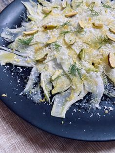 a blue plate topped with shaved cabbage and nuts