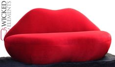 a large red couch sitting on top of a black table next to a white wall