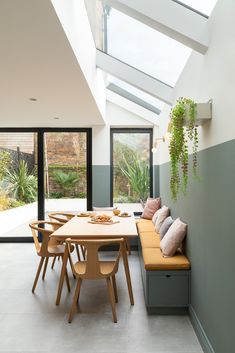 a dining room table and bench in the middle of an open floor plan with skylights