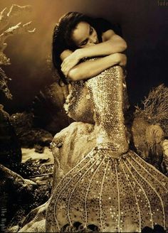 a woman in a gold sequined dress posing for a photo with her arms crossed