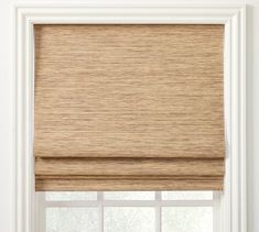 a window with a tan roman blind in front of the window and white wall behind it