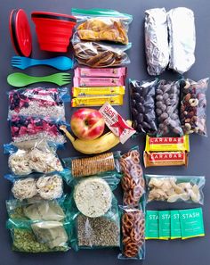 an assortment of food is laid out on a gray surface with plastic forks and spoons