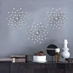 two white vases sitting next to each other on a shelf in front of a gray wall