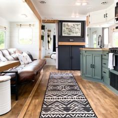 a living room and kitchen area in a mobile home with wood flooring, blue cabinets, and leather couches