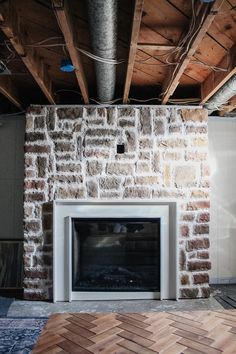 a brick fireplace in an unfinished room with exposed wood flooring and metal piping