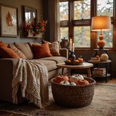 a living room filled with furniture and lots of fall decorations on the coffee table in front of a large window