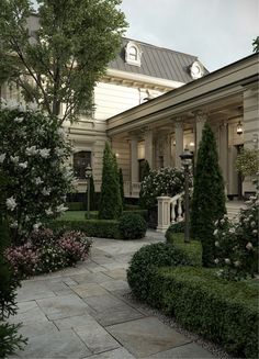 a large house with lots of trees and bushes in front of the entrance to it