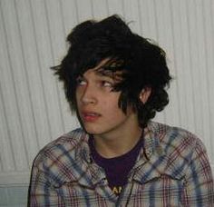 a young man with black hair wearing a plaid shirt