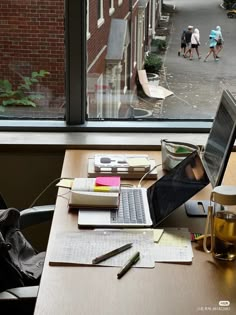 an open laptop computer sitting on top of a wooden desk next to a glass window