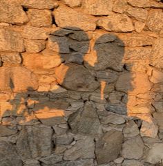 the shadow of two people on a stone wall