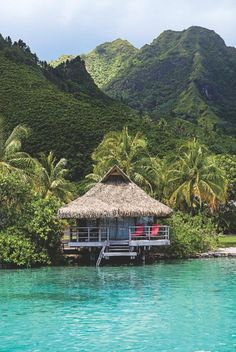 a hut on the water surrounded by palm trees