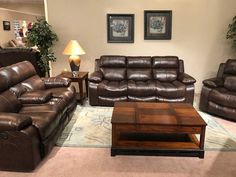 a living room filled with brown leather couches and recliners next to a coffee table