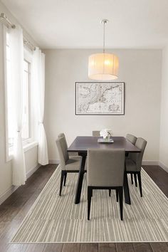 a dining room table with chairs and a rug on the floor