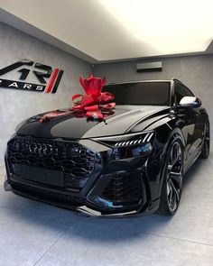 a black car with a red bow on it's hood in a showroom