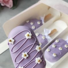 a purple cake in a box with white flowers on it