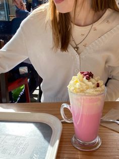 a woman sitting at a table in front of a cup filled with ice cream and cranberries