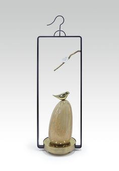 a bird is sitting on top of a vase in the shape of a glass case