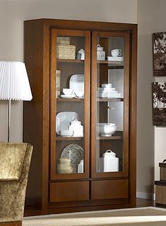 a living room with a china cabinet in it's center and a lamp on the side