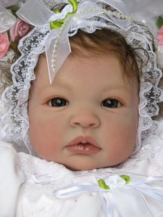 a close up of a baby wearing a white dress and headband with flowers on it