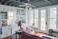 a living room filled with furniture and lots of white cabinets next to a kitchen area