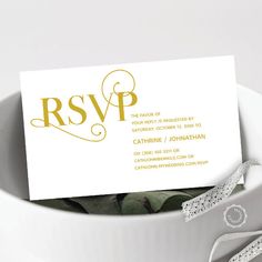 a white and gold wedding card in a bowl with ribbon on the side that says rsvp