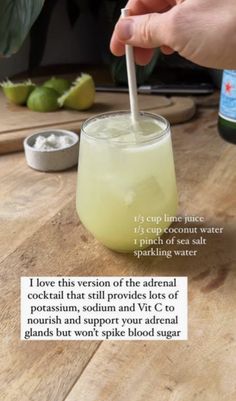 a person is holding a spoon in a drink with limes and other ingredients around it