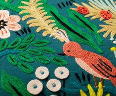 an embroidered pillow with flowers and birds on it's sides, surrounded by buttons