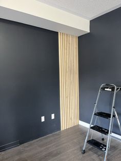 a ladder is in the middle of a room with gray walls and wood trimming