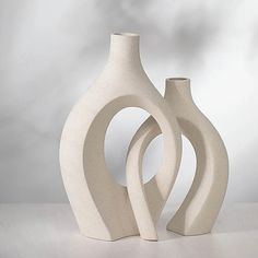 two white vases sitting next to each other on a table