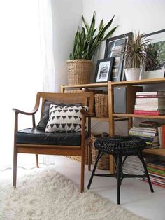 a living room filled with lots of books and plants on top of a book shelf