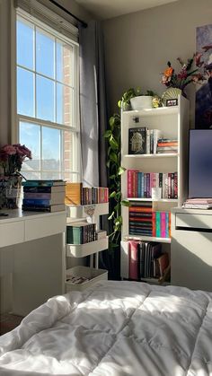 a bedroom with a bed, desk and bookshelf next to a large window