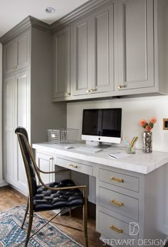 a desk with a computer on top of it in front of some cabinets and drawers