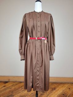 "Brand: Adele Simpson  Size: 26\" waist; see measurements  Color: brown/red Fabric Content: Polyester    Features:  Beautifully constructed Adele Simpson dress with numerous designer details. Shirtwaist dress with six rows of miniature pleats at bodice front, neckline and the cuffs. Front is closed with covered buttons. Long sleeves are elegantly gathered at the shoulder and wrist. Bodice back has shoulder darts for tailored fit. Gathered skirt is stitched to the gathered bodice at the waist. Matching patent leather belt.   Measurements: Neck: 14in  Bust/Chest:36in  Waist: 26in  Belt: 27in-32  Hip: 38in  Shoulder to Shoulder: 14in  Sleeve  Length: 24in  Center Back Length: 44in    Condition: Very Good Vintage Condition - skirt hem has been professionally repaired.   Care: Dry clean only  V Retro Brown Dress For Fall, Retro Vintage Dress For Fall Daywear, Brown Vintage Dress For Fall, Retro Brown Dresses For Daywear, Retro Midi Vintage Dress For Fall, Retro Brown Dress For Daywear, Classic Brown Dresses For Daywear, Vintage Dress With Buttons For Fall Daywear, Vintage Buttoned Dress For Fall Daywear