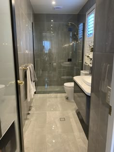 a bathroom with a walk in shower next to a white toilet and sink under a mirror