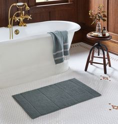 a bathroom with a bathtub, stool and rug