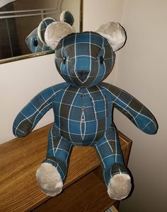 a blue teddy bear sitting on top of a wooden dresser next to a mirror in a room