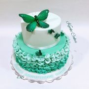 a three tiered cake decorated with green and white icing, butterflies on top