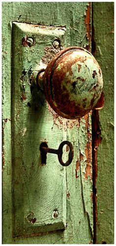 an old green door with a rusted knob and keyhole on the front handle