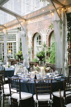 an outdoor dining area with blue linens and white tablecloths, lit by string lights