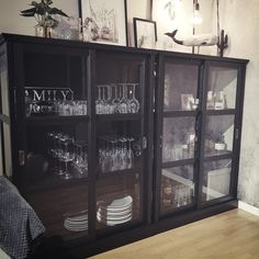 a black china cabinet filled with glasses and plates