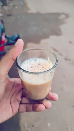 a person holding up a small cup with liquid in it